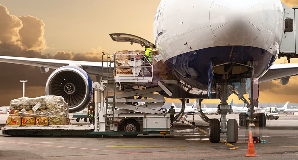 a worker using a lift to load a cargo plane